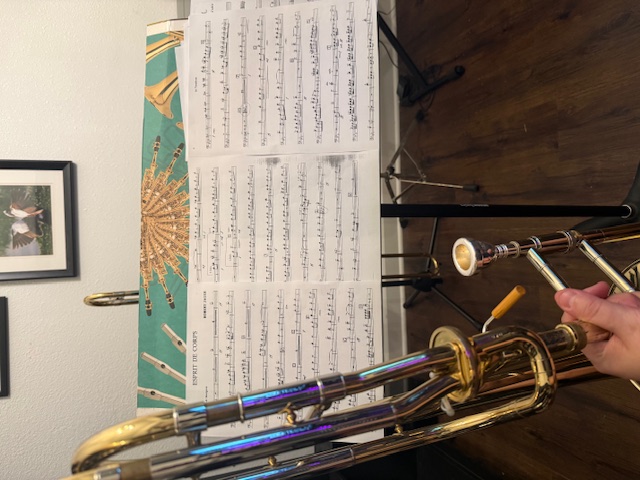 holding trombone in front of music stand with 1st trombone part on espirit de corps